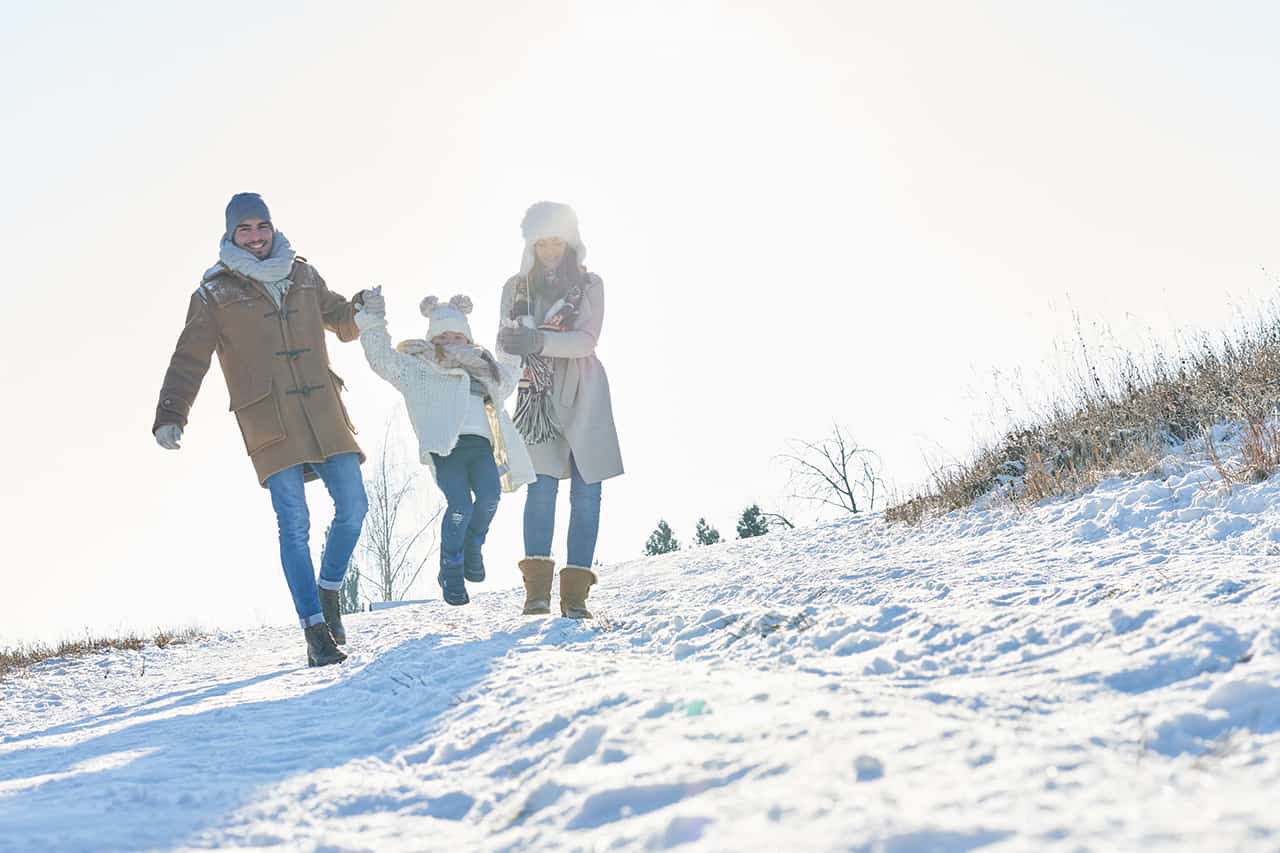 Mutter, Vater und Kind gehen einen Winterwanderweg in Lenggries